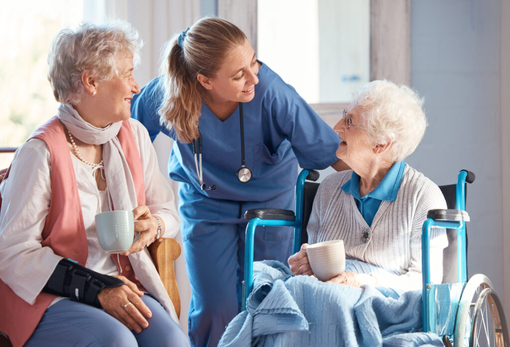 Nursing home, care and nurse with senior women doing healthcare checkup, examination or consultation. Medical, conversation and elderly woman in wheelchair consulting a doctor at retirement facility